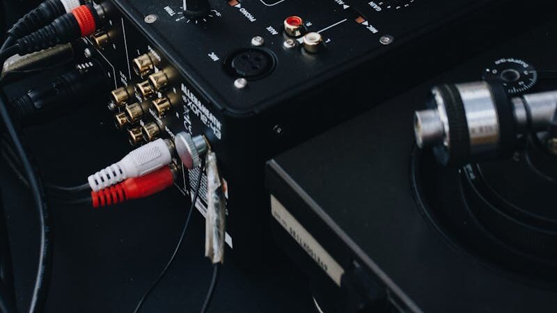 DJ adjusting controls on a music mixer, showcasing a close-up of the device with a turntable in view.