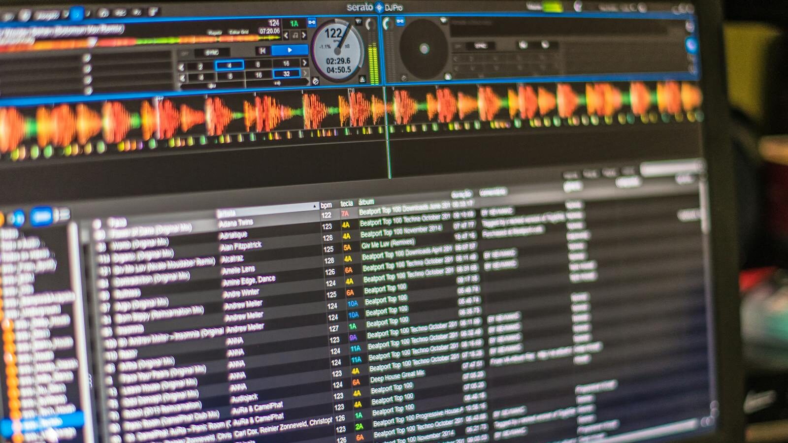 A detailed view of DJ mixing software open on a laptop screen, showcasing tracks and waveforms.